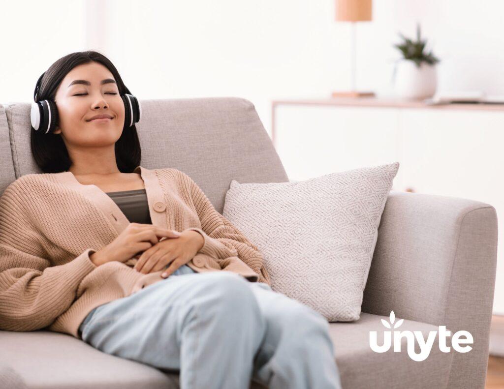 Young woman of Asian descent sitting on couch, relaxed, with headphones on